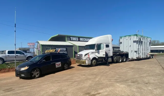 TCB Escorts pilot car with roof sign and antenna next to a tractor-trailer hauling an oversize load